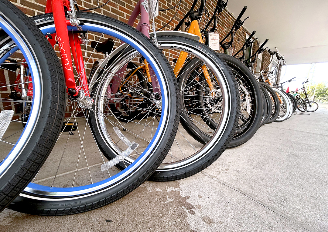 A line of bikes in a rack against a wall.